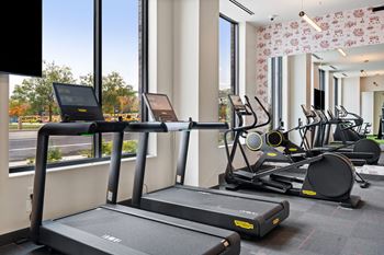 a row of treadmills in the gym of a hotel room